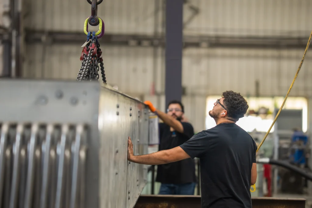 Two Hayden employees working in facility, hoisting a large piece of equipment